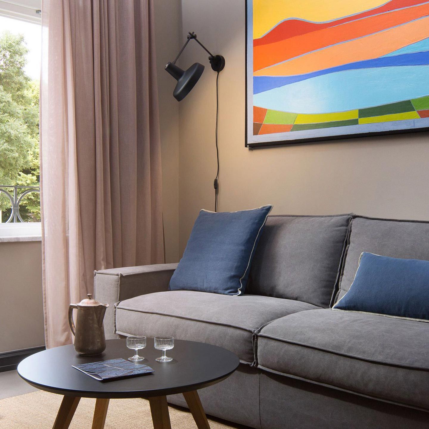 Luxurious living room adorned with a plush couch, elegant coffee table, and a captivating painting. Experience the opulence of Almayer Art & Heritage Hotel Deluxe Mezzanine Double Room Interior