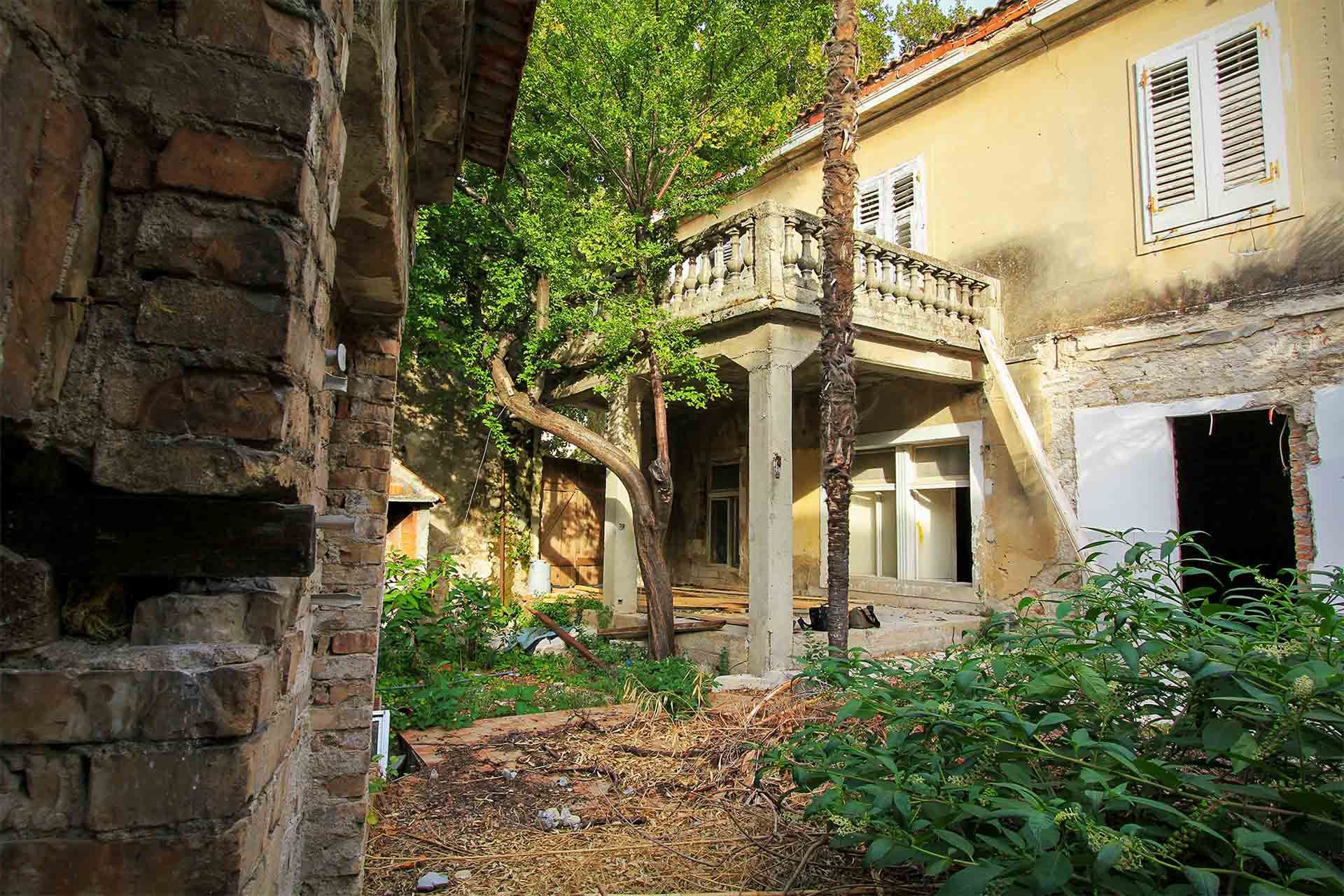 Step into the past with a glimpse of the derelict building's inner courtyard, adorned with a balcony and a tree, soon to be reborn as the Almayer Art & Heritage Hotel in Zadar Old Town in Croatia before reconstruction in 2015.