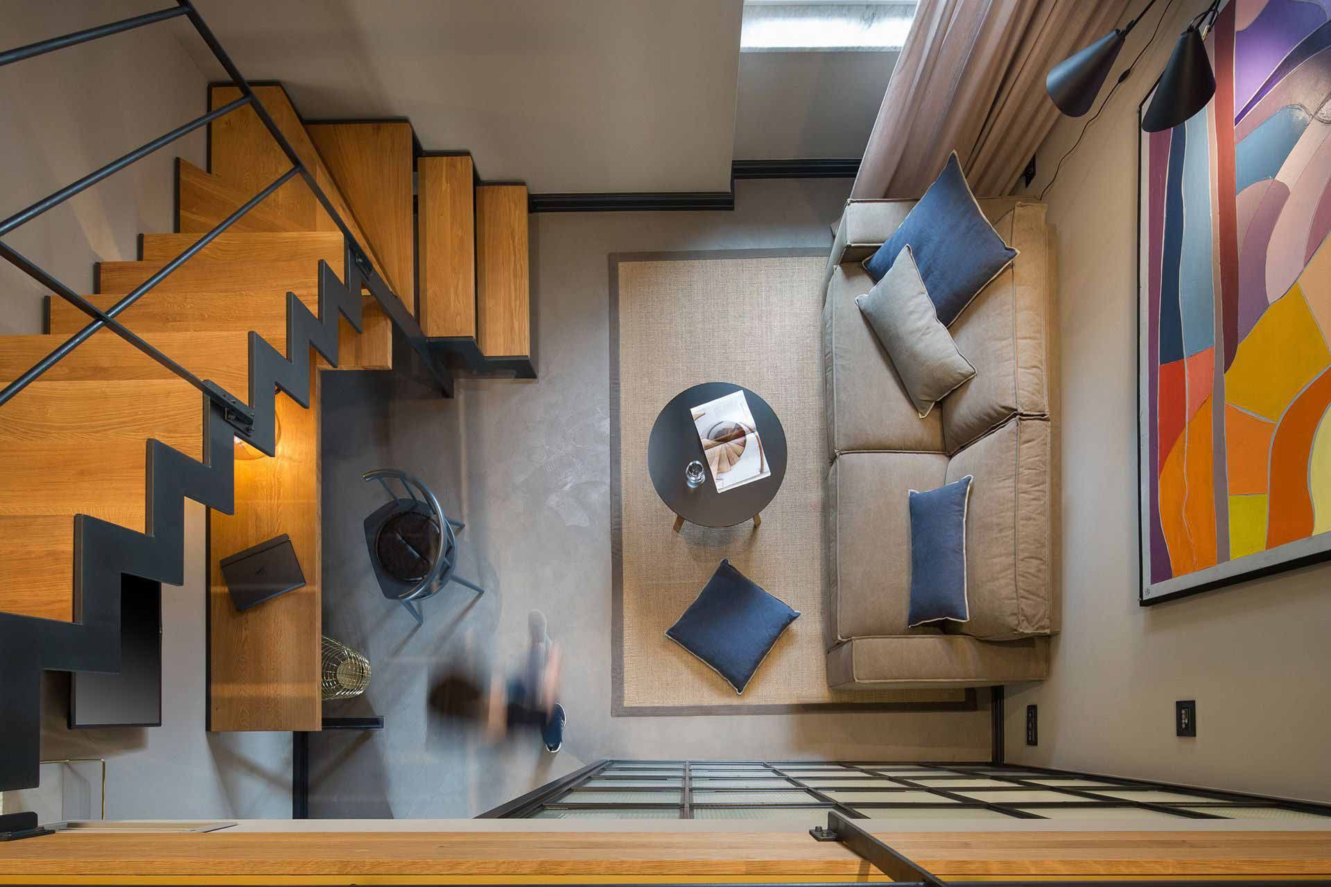 Deluxe double room with mezzanine in Almayer Hotel featuring eclectic interior design with steel staircase, pull-out sofa, elaborate woodwork, and glazed steel bathroom partition