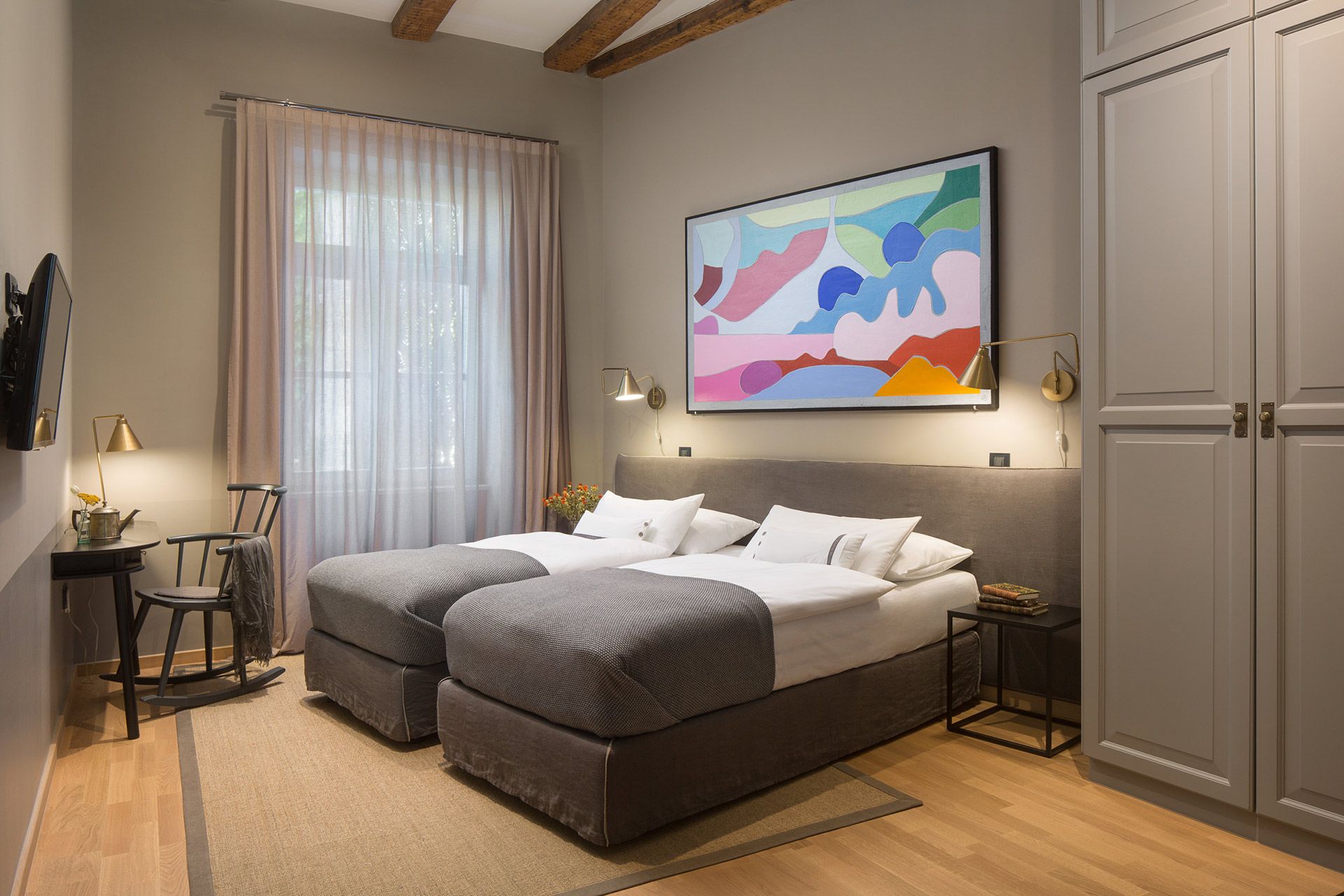 Spacious Almayer hotel’s standard double room Garbin with its king-size bed separated into twin beds, painting